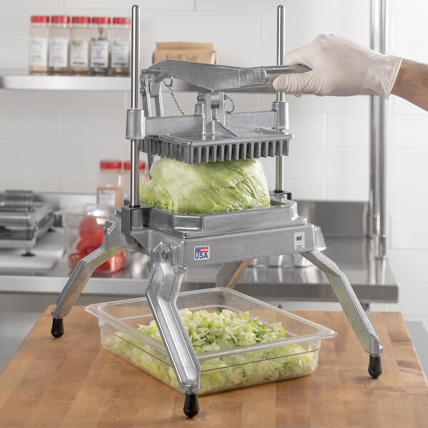 A person using a Nemco Easy LettuceKutter machine to cut lettuce.