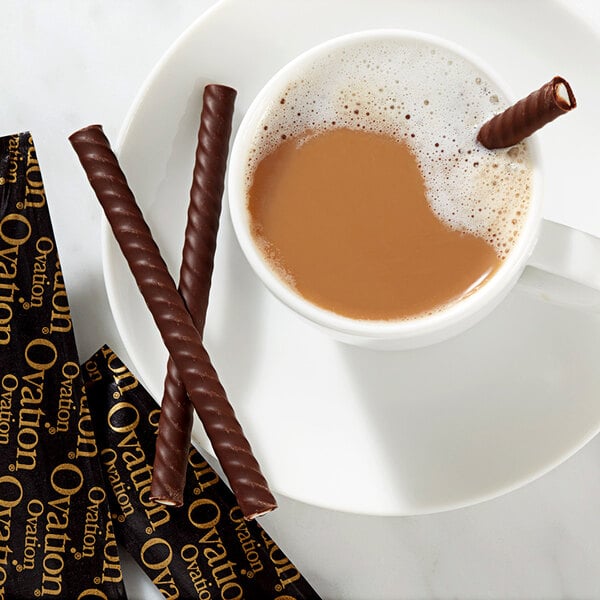 A cup of coffee with HERSHEY'S Ovation dark chocolate mint sticks on a plate.