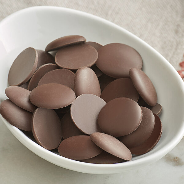 A bowl of Guittard dark chocolate wafers on a table.