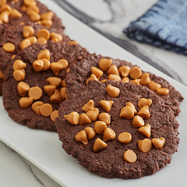 A plate of chocolate cookies with small brown caramel chips on top.