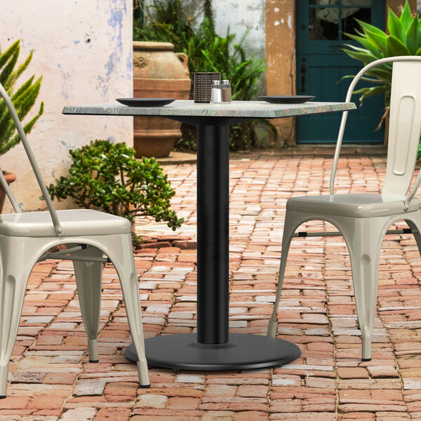 A Lancaster Table & Seating Excalibur outdoor table base with chairs on a brick patio.