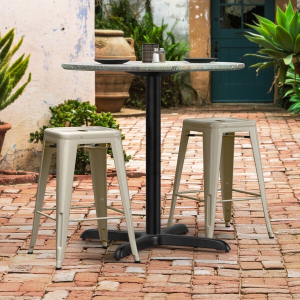 A Lancaster Table with Excalibur Black Table Base and Stools on a Brick Patio