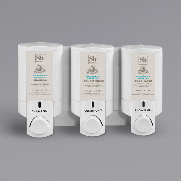 A white Dispenser Amenities Aviva 3-chamber wall mounted shower dispenser with a label on it.