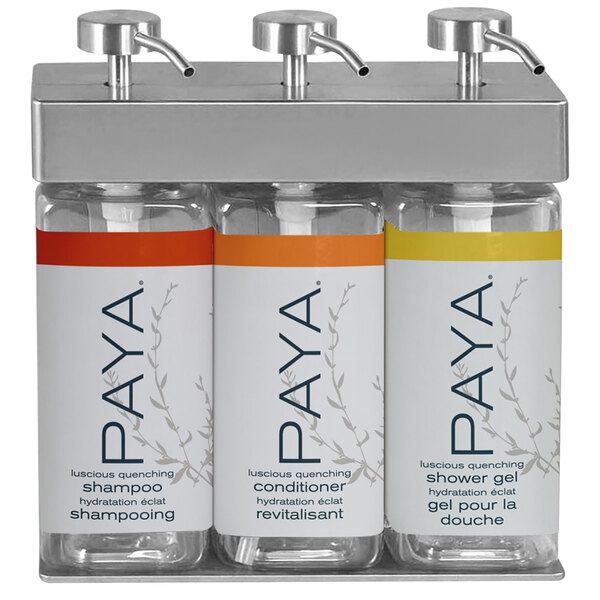 A white rectangular wall mounted dispenser with three chambers holding white rectangular bottles with black Paya labels.