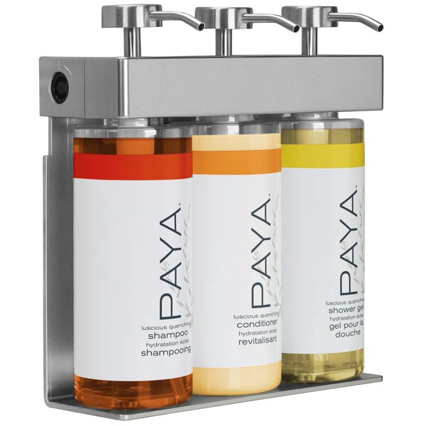A white Dispenser Amenities wall-mounted soap dispenser with 3 oval Paya bottles with black labels.