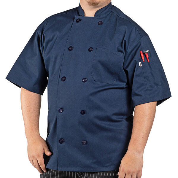 A man wearing a navy blue Uncommon Chef short sleeve chef coat with customizable embroidery.