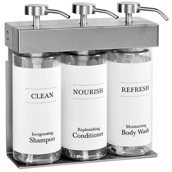 A white wall-mounted dispenser with three oval bottles with white labels.