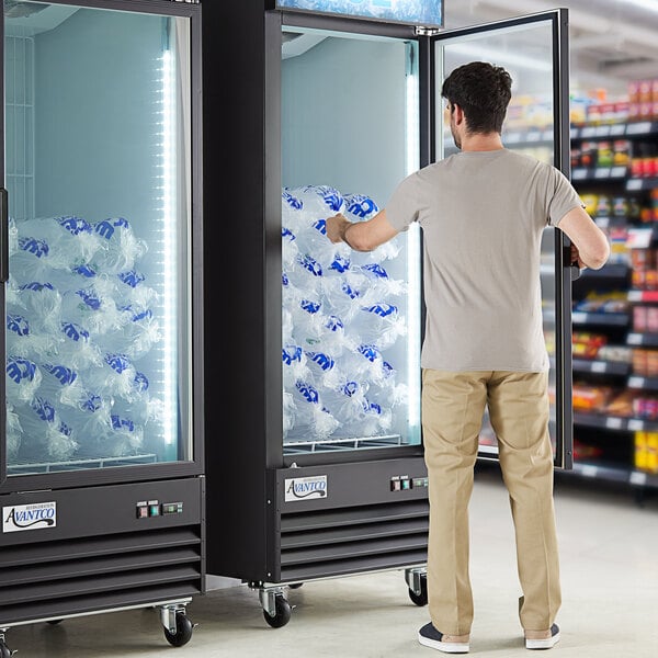 A man standing in front of an Avantco ice merchandiser with a customizable panel.
