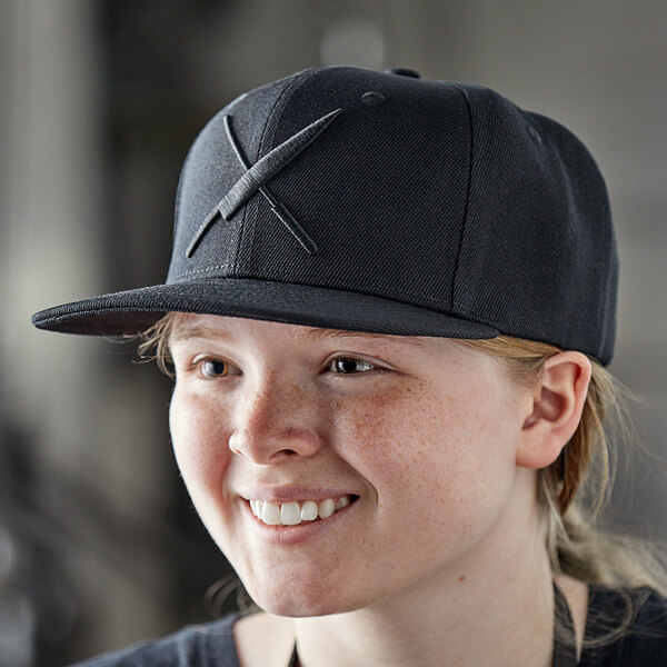 A woman wearing a black Mercer Culinary snapback hat with a large black logo.