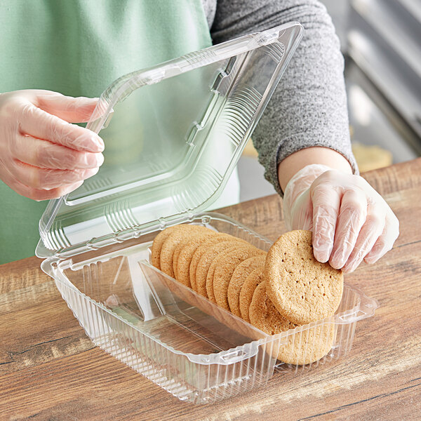 A hand holding a Polar Pak clear plastic container of cookies.