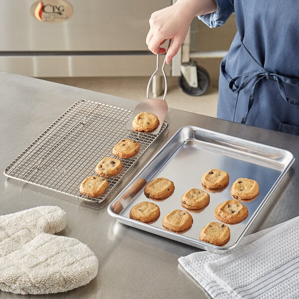 A person putting cookies on a Choice aluminum sheet pan.