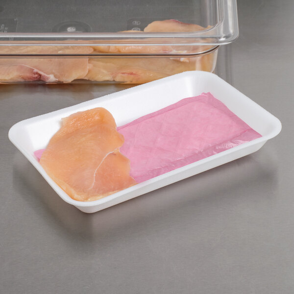 A white foam supermarket tray with pink absorbent meat pads holding meat.