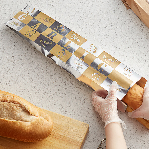 A person in gloves using a Bagcraft foil wrapper to hold a bread roll.