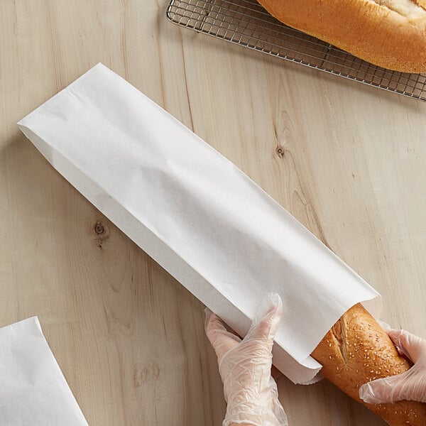 A person holding a bag of bread in a Bagcraft white paper bread bag.