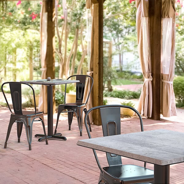 A Lancaster Table & Seating Excalibur dining table and chairs on a brick patio.