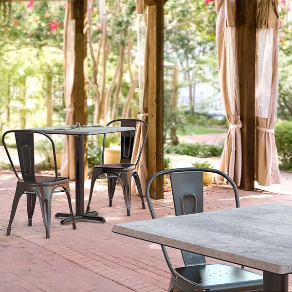 A Lancaster Table & Seating Excalibur square dining table and chairs on a brick patio.