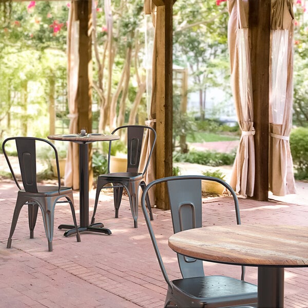 A Lancaster Table & Seating Excalibur round dining table with textured Yukon oak finish and chairs on an outdoor patio.