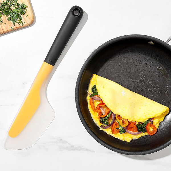 An OXO high heat flexible silicone omelet spatula turning an omelet in a pan.