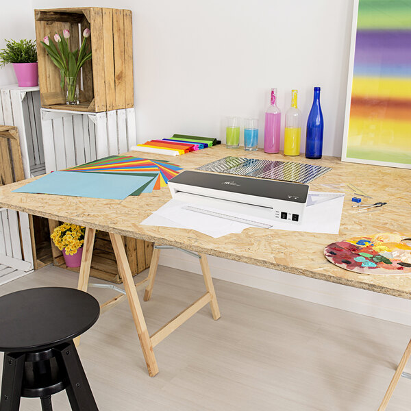 A Royal Sovereign white glass-top laminator on a colorful striped table.