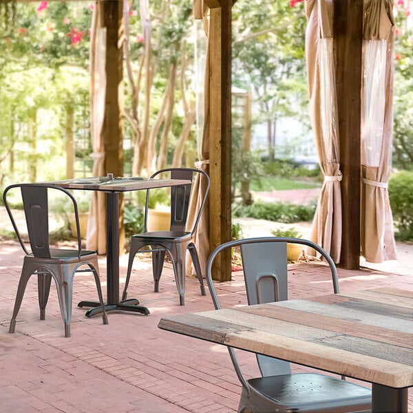 A Lancaster Table & Seating square dining height table with a textured mixed plank finish on an outdoor patio.