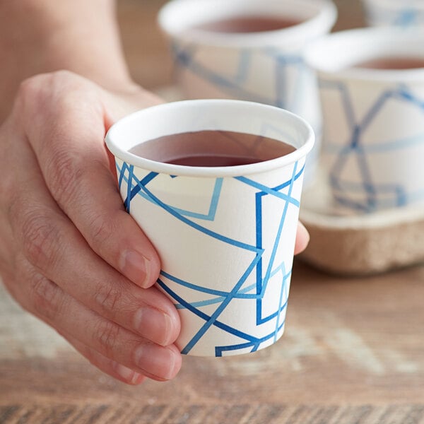 A hand holding a Choice paper cold cup with a liquid in it.