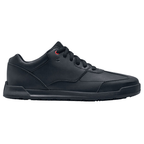 A black Shoes For Crews women's athletic shoe with red and blue laces.