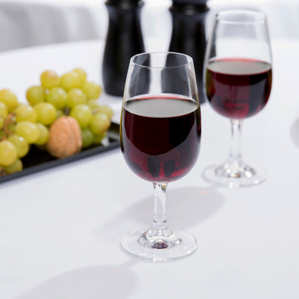 Two Stolzle INAO wine glasses filled with red wine on a table.