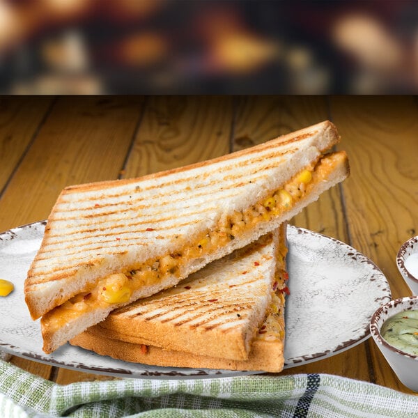 A grilled sandwich with cheese and vegetables on a GET French Mill melamine plate.