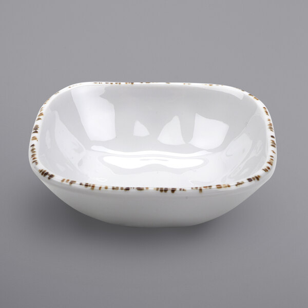 A white bowl with brown specks on it.