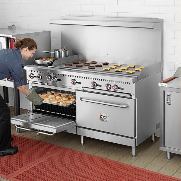 A woman putting food into a large oven in a professional kitchen.