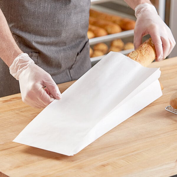 A person in gloves holding a bag of bread.