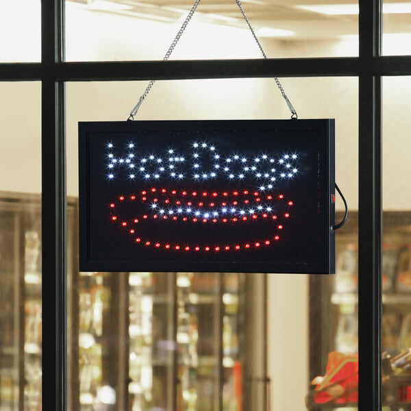 A rectangular LED sign that says "Hot Dogs" hanging in a window.