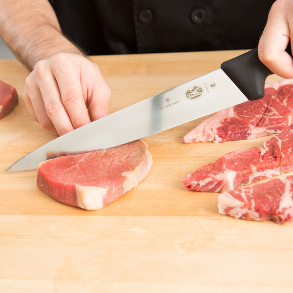 A person using a Victorinox semi-flexible carving knife to cut meat on a cutting board.