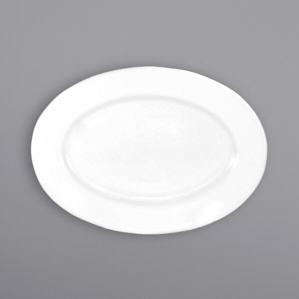 An International Tableware white porcelain oval platter with a wide rim on a gray surface.