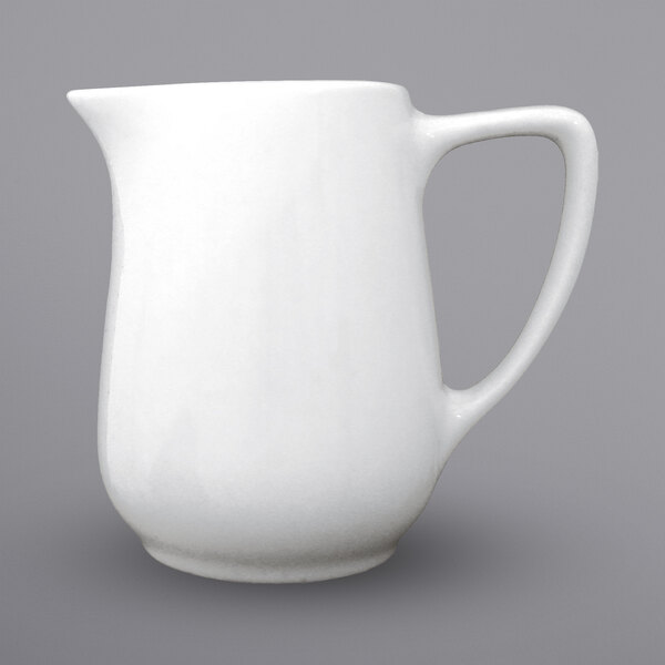 A white International Tableware porcelain creamer with a handle.