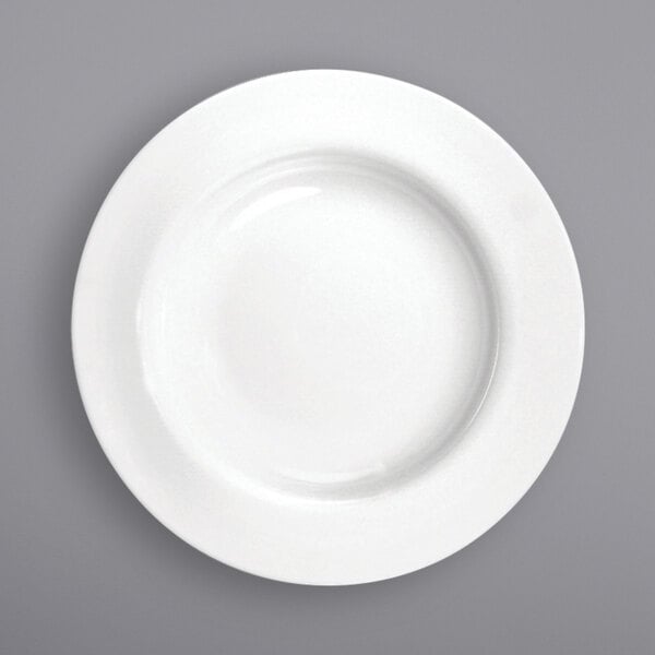 A close-up of a International Tableware bright white porcelain plate with a wide rim.