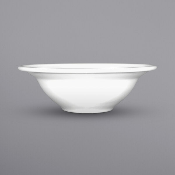 A close up of an International Tableware bright white porcelain grapefruit bowl with a rolled edge.