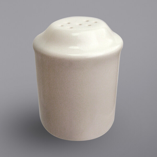 A white ceramic International Tableware salt shaker with holes.