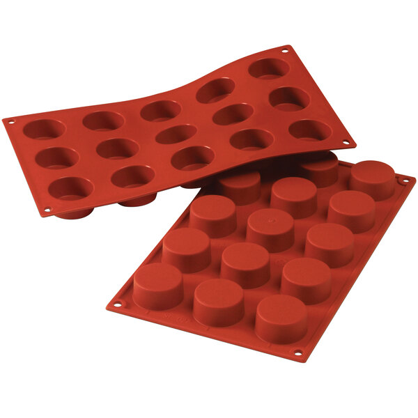 A close-up of a red Silikomart silicone baking mold with cylindrical cavities.