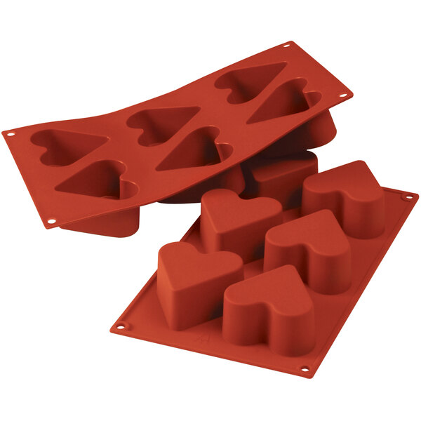 A red Silikomart silicone baking mold with heart shaped cavities.