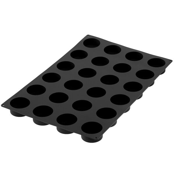 A black Silikomart silicone baking mold with cylindrical cavities.