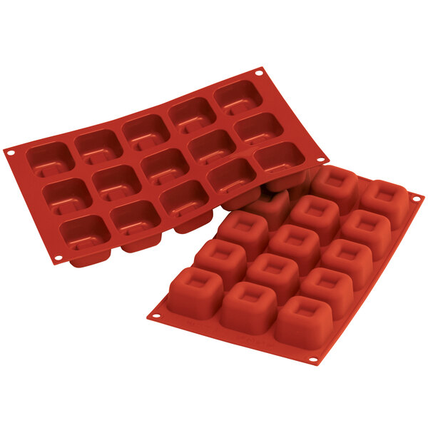 A close-up of a red Silikomart silicone baking mold with 15 square cavities.