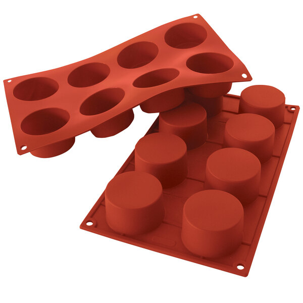 A red Silikomart silicone baking mold with cylinder-shaped cavities.