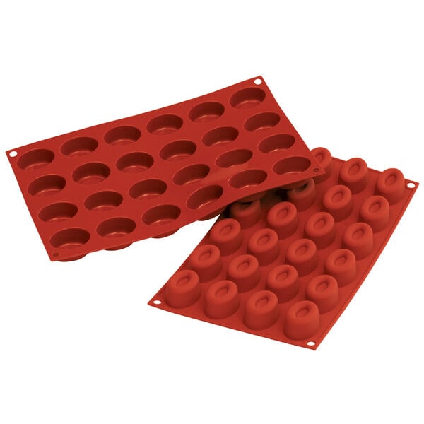 A couple of red Silikomart silicone baking trays with small oval cavities.