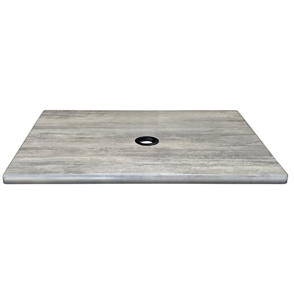 A grey square table top with a black circle and a hole in the middle.