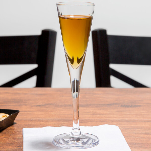 A Stolzle liqueur glass filled with a liquid on a table.