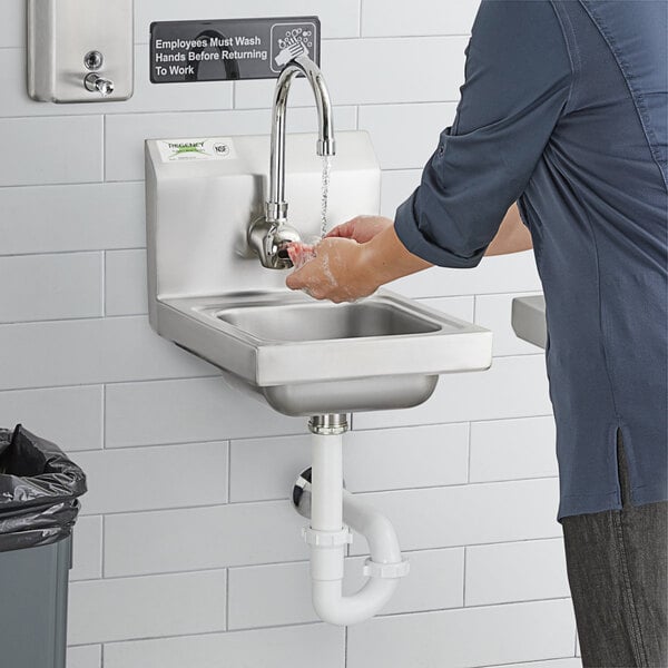 A person washing hands in a Regency wall-mounted hand sink.