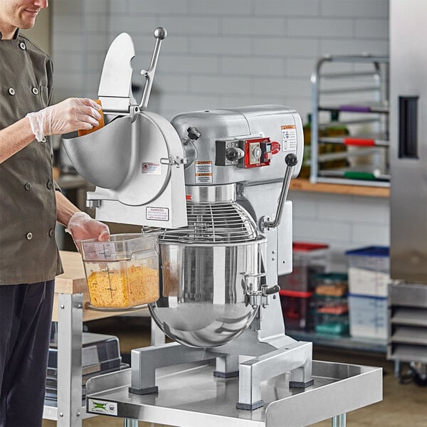 A man in a chef's uniform standing next to a white Avantco planetary stand mixer.