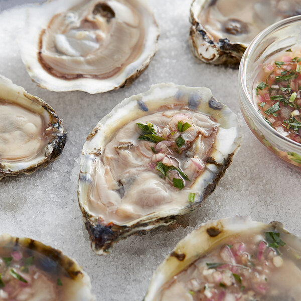 A group of Rappahannock Rochambeau oysters on ice on a white surface.