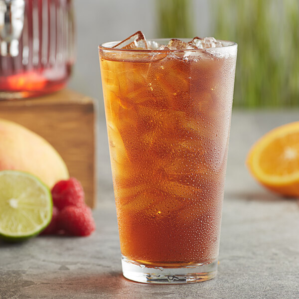 A glass of Bromley iced tea with ice, oranges, and fruit.